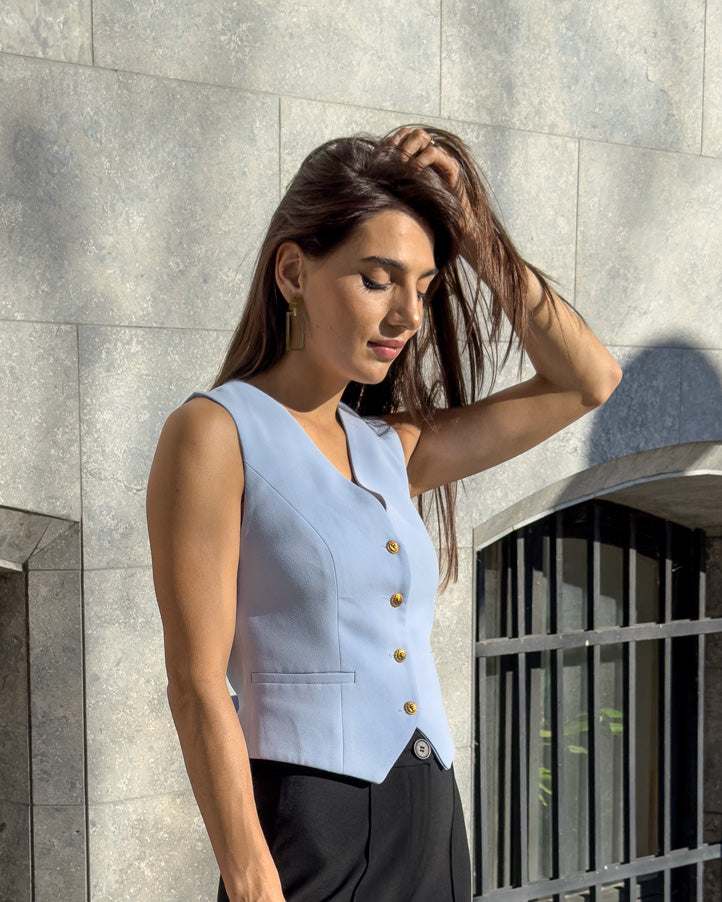 Vesta damă albastră cu croi cambrat și nasturi, din stofă ușor elastică.